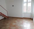 Empty room with white walls, tiled floor, large window, staircase