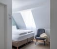 bedroom with bed, chair, rug, window, lamp, thermostat