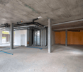 Empty basement room with unfinished design, exposed ceiling, and visible utilities