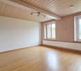 empty room with wooden floors, white walls, two windows, wooden ceiling, wall-mounted radiator