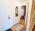 white walls, wooden floor, mirror, wardrobe with rack, rug, curtains