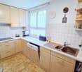 modern kitchen, wooden cabinets, stainless steel appliances, dishwasher, washing machine, tiled backsplash, white countertops