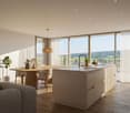 Open plan room with wooden floor, dining table, gray couch, kitchen island, large glass window