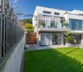 Modern white house, large glass windows, balcony with glass railing, two garages, well-maintained garden