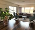 living room with hardwood floors, large windows, couch, coffee table, chairs, floor lamp, large potted plant