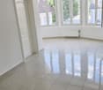 Spacious room with large windows, white walls, and a tiled floor with a glossy finish. The room appears to be empty, ready for furnishing and decorating.
