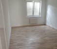 Empty room with white walls, wooden floor, and a window with blinds
