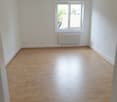 Empty room with white walls, wooden floor, window with white frame and radiator