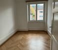 empty room with wooden floor, white walls, and a window