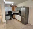 Open kitchen with refrigerator, countertop, built-in oven, cabinets, and tiled floor.