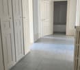 Empty room, tiled floor, two white doors, open door leading to another room