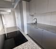 Modern kitchen with granite countertops, built-in sink, induction stovetop, white cabinets, and a stainless steel faucet