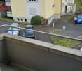 balcony, cars parked in front, building with multiple windows, small garden
