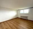 Empty room with white walls, hardwood flooring, and a window providing natural light.