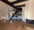 Empty room with wooden floors, kitchen, fireplace, wooden beams