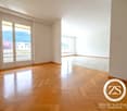 Spacious room with hardwood floors, sliding glass doors to balcony, large windows with views, white walls