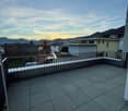 Balcony with metal railing, tiled floor, beautiful sunset view over mountains