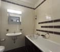Bathroom with black and white tile, bathtub, sink, and mirror cabinet
