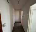 empty hallway, white walls, dark floor, small light on ceiling