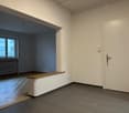 empty room, wooden floor, white walls, wooden bench, power outlets, windows with view