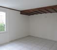 empty room with white tiles, white walls, large window, wooden beam