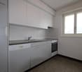 Modern kitchen, white cabinets, granite countertops, stainless steel sink, dishwasher, oven, white tiled walls, window