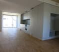 Spacious room with large windows, white cabinets, wooden floor, modern kitchen with appliances