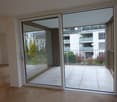 sliding glass doors to a balcony, wooden floor, high ceiling, glass walls, white walls