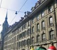 large building with many windows, multiple floors, street with people and bicycles