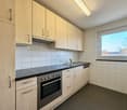 Wooden cabinets, tiled walls, black countertop, stainless steel oven and stove, dishwasher, washing machine