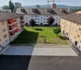 Aerial view of residential complex with a green courtyard, red awnings, a playground, and buildings