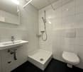 modern white tiled bathroom, white shower, white sink, modern toilet, modern mirror