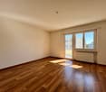 empty room, wooden floor, sliding glass doors leading to balcony, white walls, radiator