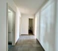 Empty hallway, tiled floor, white walls, doors on both sides, bathroom on the right