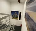 A white painted interior with steps leading up and fire extinguisher and artwork on wall.