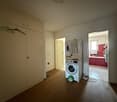 Large cabinet, white appliances, red tiles in background, washing machine, dryer