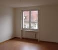 Spacious room with large windows, hardwood floor, and radiator