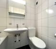 white tiled walls, white sink, white toilet, mirror above sink, bathtub