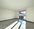 Empty room, white walls, wooden floor, sliding glass doors leading to balcony