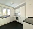 white kitchen, granite countertop, stainless steel dishwasher, oven, black floor