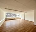Empty room with wooden floors, windows, and ceiling lighting