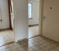 Empty room with tiled floor, white walls, two doors, and a window with a view outside