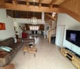 Living room with wooden ceiling, spiral staircase, couch, coffee table, TV, wooden entertainment center