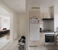 Open-plan living and kitchen area, with white tiles, modern kitchen appliances, washing machine visible