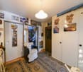 Entrance hall with a chair, rug, mirror, and coat rack. Wall decorations include pictures and leaves.