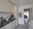 modern kitchen, white cabinets, black countertops, stainless steel sink, dishwasher, washing machine, open door to living room