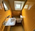 Small bathroom with yellow tile walls, a sink, toilet, and a window