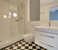 white tiles, glass walk-in shower, white toilet, white vanity, white sink