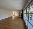 Spacious living room with hardwood flooring, large windows, and access to a balcony or terrace.