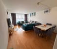 wood floor, window with curtains, chandelier, table with chairs, sofas, coffee table, TV, decorative objects, paintings on wall